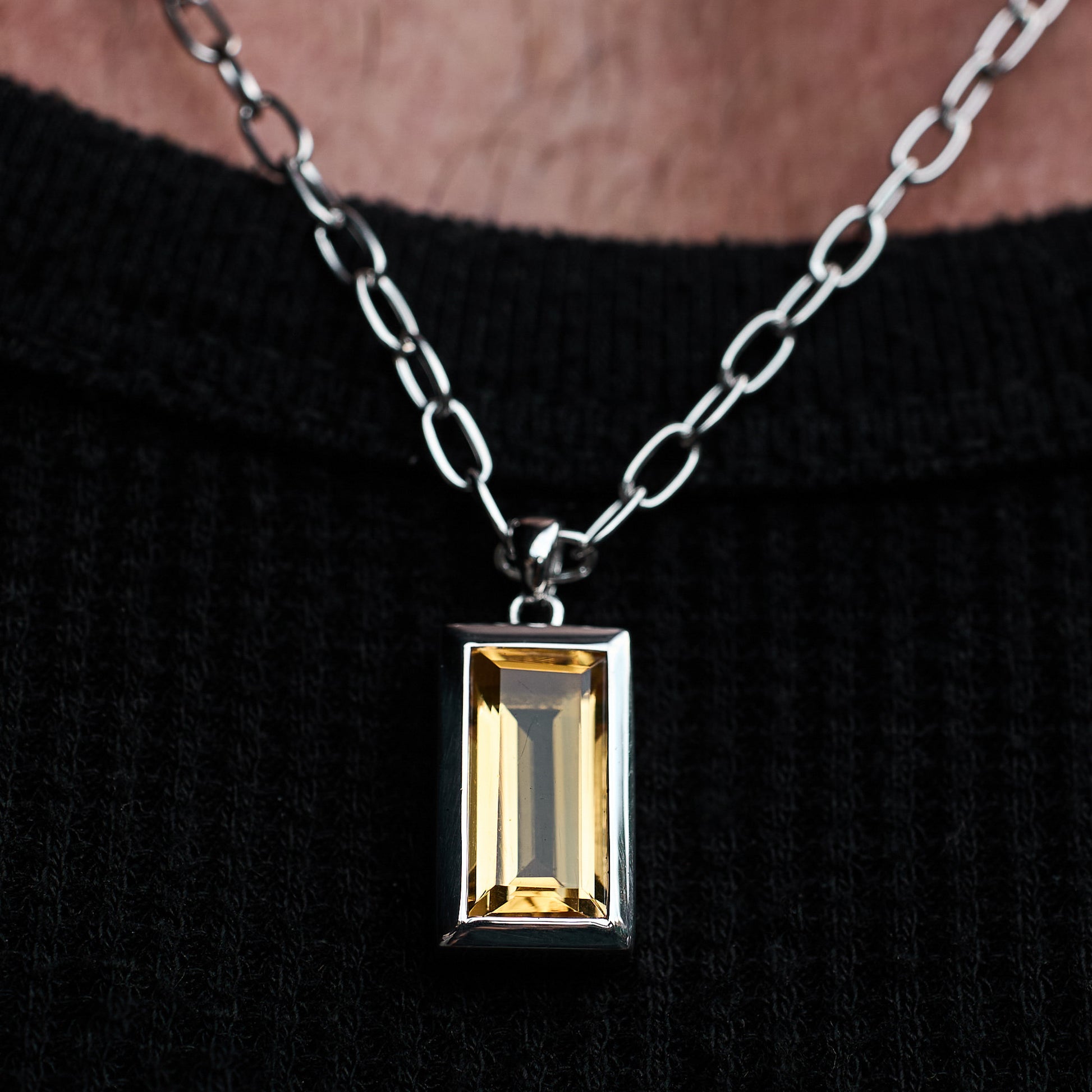 Close-up of a person wearing the Citrine Pendant, featuring a baguette-cut citrine stone set in rhodium-plated sterling silver with a 55cm sterling silver chain.