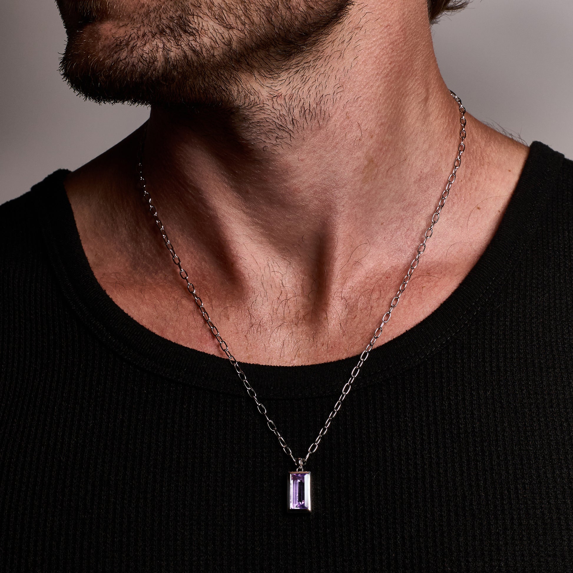 Close-up of a person wearing the Amethyst Pendant, featuring a natural baguette-cut amethyst stone set in rhodium-plated sterling silver with a 55cm sterling silver chain.